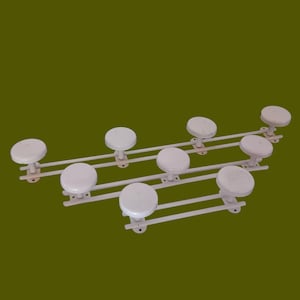 May include: White metal coat rack with eight round hooks. The hooks are attached to a metal bar that is mounted to the wall.