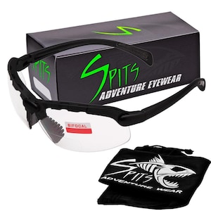 May include: Black bifocal safety glasses with a clear lens and a red "Bifocal" label. The glasses are in a black box with the green text "SPITS ADVENTURE EYEWEAR". The glasses also come with a black pouch with the white text "SPITS ADVENTURE WEAR" and a white graphic of a fish.