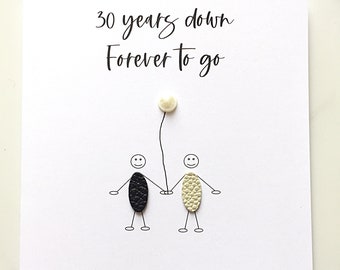 May include: A white greeting card featuring the black text 30 years down Forever to go. Below the text are two stick figures with textured oval bodies, one black and one cream, holding hands and a single cream-colored balloon.