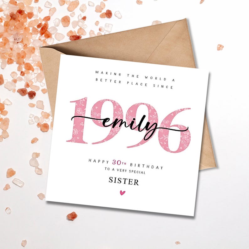 May include: A square white greeting card with a brown envelope. The card features the pink floral patterned text 1996, the name emily in black script, and the text MAKING THE WORLD A BETTER PLACE SINCE, HAPPY 30TH BIRTHDAY TO A VERY SPECIAL SISTER.