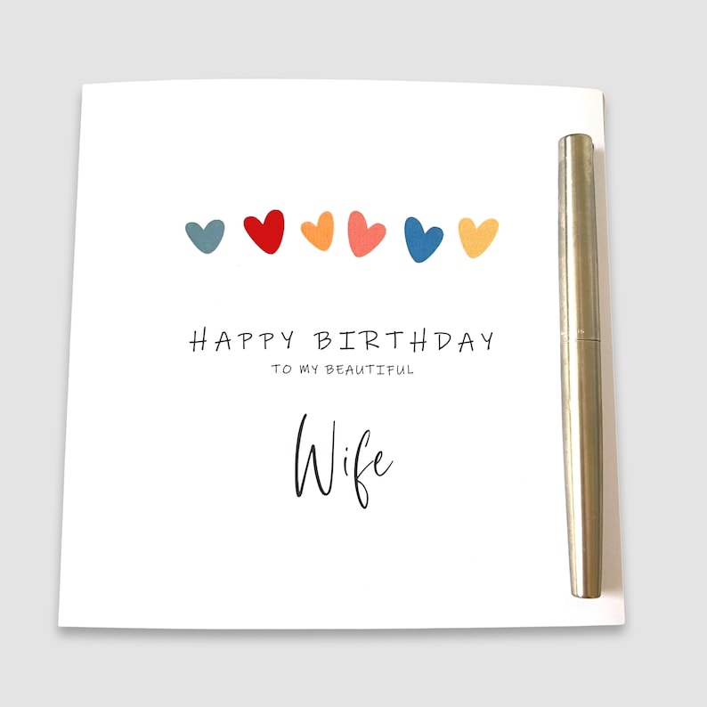 May include: A white card with a colorful row of hearts and the text "Happy Birthday to my beautiful Wife".
