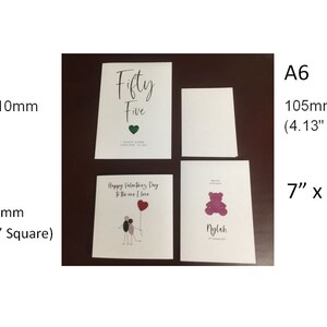 May include: Four blank greeting cards in different sizes, including A5 (5.8" x 8.3"), A6 (4.13" x 5.83"), and square (just under 6" square). The cards are white with a smooth finish. One card has the text "Fifty Five" printed on it.