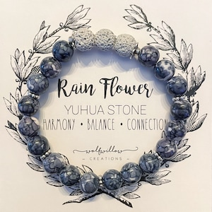 Puede incluir: Un brazalete de piedra Yuhua Rain Flower. El brazalete presenta cuentas estampadas en azul oscuro y blanco, intercaladas con cuentas de piedra de lava gris. La tarjeta detrás del brazalete tiene el texto "Rain Flower" y "Harmony, Balance, Connection."