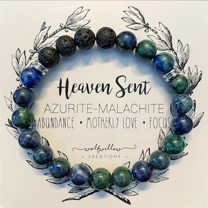 May include: An Azurite and malachite gemstone bracelet with black lava beads and silver spacers. The bracelet is on a white card with the text "Heaven Sent Azurite-Malachite Abundance • Motherly Love • Focus wolfwillow CREATIONS".