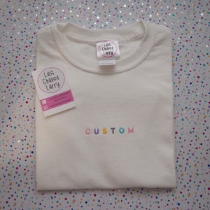 Custom block text embroidered t-shirt. Pastel rainbow font.