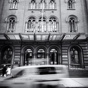 May include: A black and white photo of a building with a large arched entrance. The building has a classic architectural style with many windows and decorative details. The entrance is labeled "PUBLIC" and has a number "425" above it.