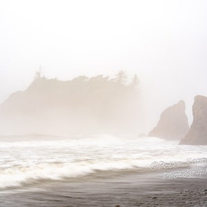 Op de afbeelding: Een mistig zeelandschap met twee rotsachtige eilanden op de voorgrond en een groter eiland op de achtergrond. Het water is ruig en de lucht is lichtblauw.