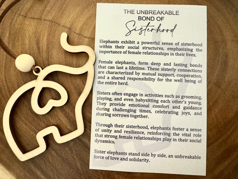 May include: A wooden elephant cutout necklace with a card that reads "The Unbreakable Bond of Sisterhood". The card describes the strong bonds of female elephants and how they support each other.