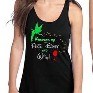 May include: Black tank top with a scoop neck and racerback design. The front features a green silhouette of a fairy, the words "Powered by Pixie Dust and Wine!" and a red wine glass.