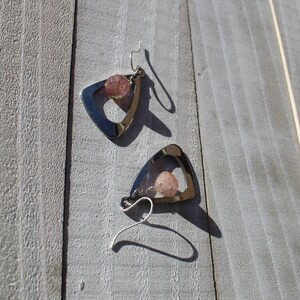May include: A pair of silver triangle earrings with pink stone accents.