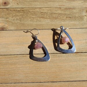 May include: A pair of silver dangle earrings with a pink gemstone hanging from each earring.