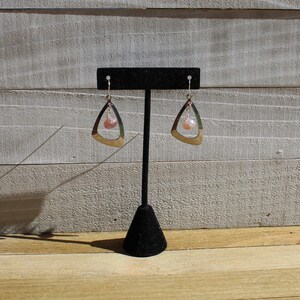 May include: A pair of silver dangle earrings with a pink and white gemstone hanging from each earring.