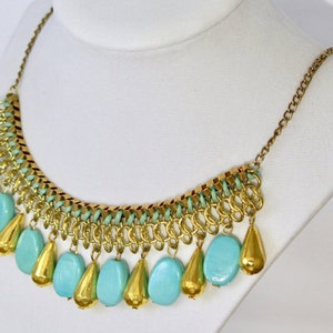 May include: A gold chain necklace with a cascading fringe of turquoise and gold beads.