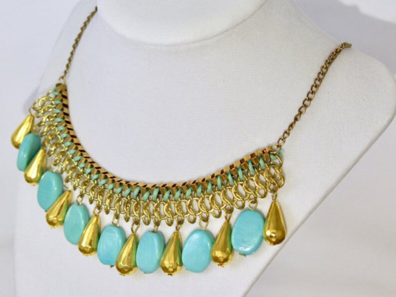 May include: A gold chain necklace with a cascading fringe of turquoise and gold beads.