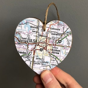 May include: A wooden heart-shaped ornament with a map of Tulsa, Oklahoma printed on it. The map shows major roads and highways, including Interstate 44, and cities like Sand Springs, Jenks, Bixby, and Broken Arrow.