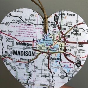 Może przedstawiać: Serce z mapą ozdobne przedstawiające mapę Madison, Wisconsin. Mapa pokazuje gł&oacute;wne drogi, autostrady i okoliczne miasta. Ozdoba jest wykonana z drewna i ma sznurek jutowy do zawieszenia.