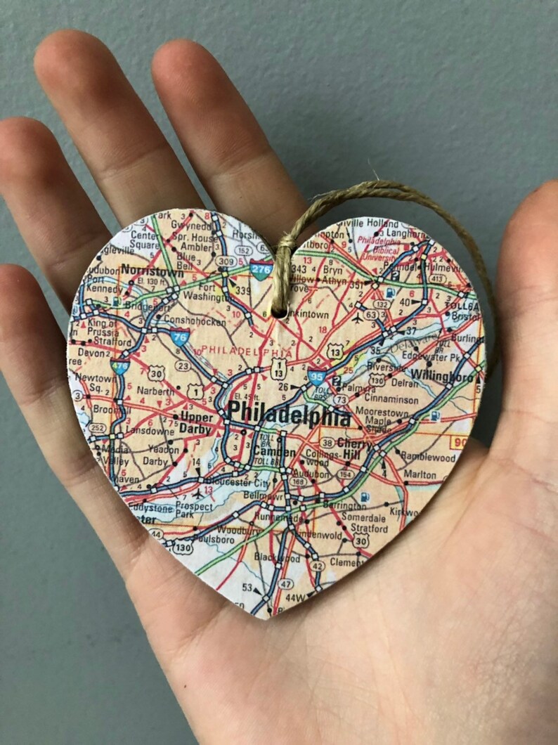 May include: A heart-shaped wooden ornament with a map of Philadelphia, Pennsylvania printed on it. The ornament has a string attached for hanging.