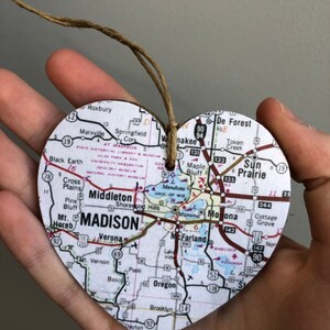 Może przedstawiać: Drewniana ozdoba w kształcie serca z nadrukowaną mapą Madison, Wisconsin. Mapa obejmuje miasta Middleton, Verona, Sun Prairie, De Forest i McFarland. Ozdoba jest przymocowana sznurkiem.