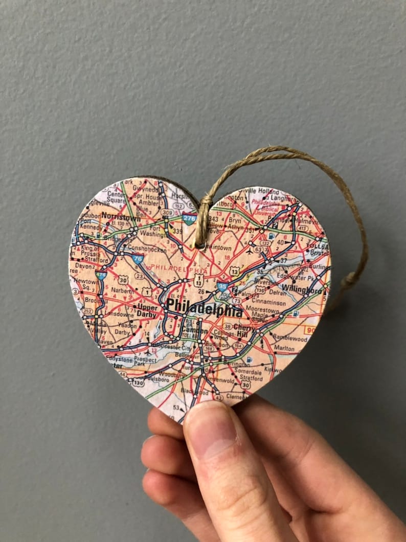 May include: A wooden heart-shaped ornament with a map of Philadelphia, Pennsylvania printed on it. The ornament has a twine string for hanging.