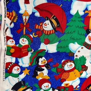 May include: A blue cotton fabric featuring a repeating Christmas pattern of snowmen and penguins. The snowmen wear hats and scarves, some holding umbrellas or books. A penguin holds an umbrella, and another is near a red mailbox. Text reads: by JOAN MESSMORE © Cranston Print Works Co. 100% cotton and printed in the U.S.A.