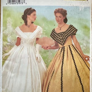 May include: A vintage sewing pattern featuring two women in historical gowns. The pattern includes sizes 12, 14, and 16. The image shows a white gown with fringe and a gold gown with black trim. The text "MAKING HISTORY" is visible.