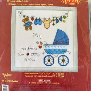 Puede incluir: Kit de punto de cruz con un diseño de bebé. El bordado incluye un osito de peluche, ropa de bebé y un cochecito azul. El tamaño final es de 20 x 20 cm. El kit incluye el texto "Boy", la fecha, las medidas y la marca "RIOLIS".