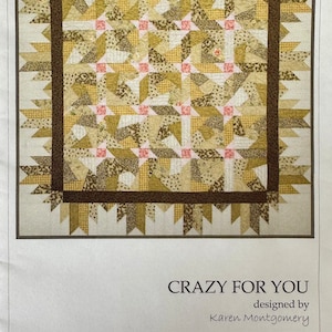 May include: A quilt pattern titled "CRAZY FOR YOU" designed by Karen Montgomery. The quilt design features a repeating pattern of tan, brown, and pink shapes. The quilt is bordered by a dark brown frame. The Quilt Company logo is in the lower left corner.