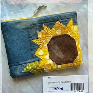 May include: A blue denim-style pouch with a large sunflower applique. The sunflower has yellow petals with white polka dots and a brown center. The pouch is labeled "Sunflower Pouch" and is 8" x 10" when finished.