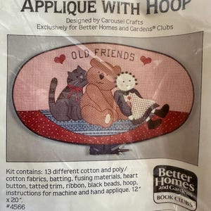 May include: An applique kit with the text "OLD FRIENDS" featuring a cat, teddy bear, and doll design. The kit includes cotton fabrics, a hoop, and instructions. The finished applique measures 12" x 20".