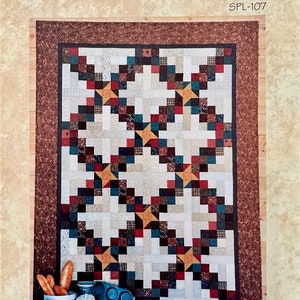 May include: A quilt pattern titled "Simple Pleasures" by Terry Atkinson, featuring a patchwork design with star patterns in various colors. The quilt has a brown border and the words "Confetti Stars" at the bottom.