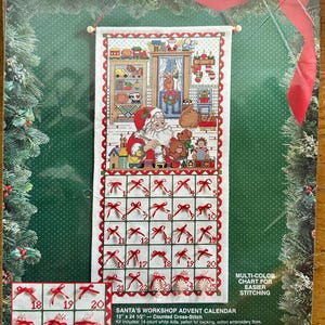May include: A Bucilla Santa's Workshop Advent Calendar cross-stitch kit. The kit features a festive design with Santa Claus, toys, and a 25-day countdown. The finished size is 12 inches by 24.5 inches. Includes floss, ribbon, and instructions.