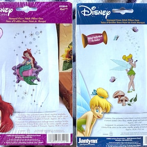 May include: Two Disney Princess stamped cross stitch pillowcase kits by Janlynn. The left kit features Ariel with a purple shell chair and star accents. The right kit features Tinker Bell with butterflies and mushrooms. Both include floss and measure 50.8 by 76.2 cm.