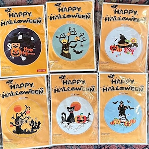 May include: Six Halloween-themed embroidery DIY art kits. Each kit features a circular design with a spooky theme, including pumpkins, bats, and haunted houses. The packaging reads "Happy Halloween" in bold letters.