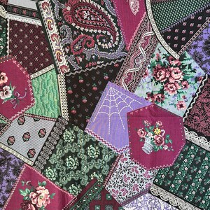 May include: A cotton fabric featuring a patchwork design with various floral, paisley, and lace patterns in shades of purple, green, black, and white. The print includes a spiderweb motif and text along the selvage reading Cranston Print Works Company.
