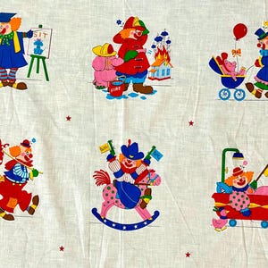 May include: White fabric with colourful cartoon clowns in different scenarios. One clown teaches a dog to sit, another is a firefighter, and others ride a rocking horse or pull a wagon. Red stars are scattered across the background.