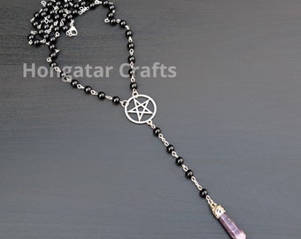 Peut inclure: Un collier de perles noires avec un pendentif pentagramme argenté et une pointe de cristal violette.