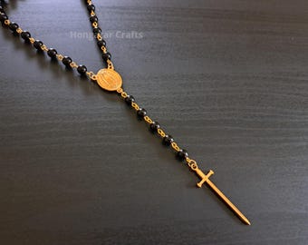 Collar corto estilo rosario con colgante de espada, tono dorado.