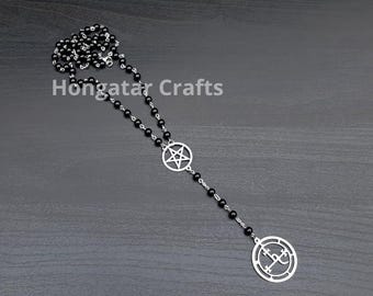 Könnte beinhalten: Eine schwarze Perlenkette mit einem silberfarbenen Pentagramm-Anhänger und einem runden Anhänger mit einem Symbol. Die Kette wird auf einer dunkelgrauen Oberfläche präsentiert. Der Text "Hongatar Crafts" ist sichtbar.