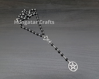 Könnte beinhalten: Schwarze Perlenkette mit einem silbernen Pentagramm-Anhänger und einem silbernen Pentagramm-Anhänger. Die Kette liegt auf einer dunklen Holzoberfläche.