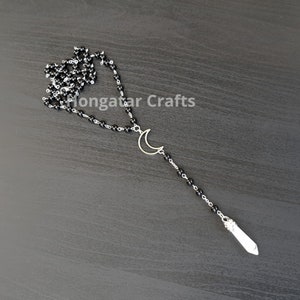 May include: A black beaded necklace with a crescent moon charm and a white crystal pendant.