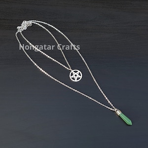 Puede incluir: Un collar de cadena de plata con dos colgantes. Un colgante es una estrella de cinco puntas de plata y el otro es una piedra preciosa verde.