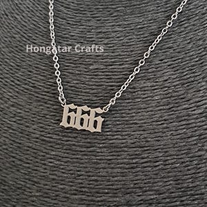 Könnte beinhalten: Eine silberfarbene Halskette mit einem Anhänger, der die Zahl 666 in einer altenglischen Schriftart zeigt. Der Anhänger ist an einer dünnen Metallkette befestigt. Der Text Hongstar Crafts ist in der oberen linken Ecke zu sehen.