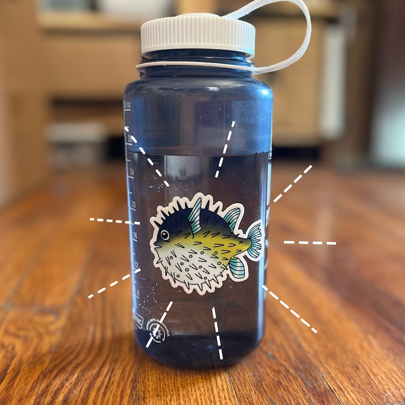 Puede incluir: Una botella de agua reutilizable azul con una tapa blanca y una pegatina de un pez globo amarillo y azul en la parte delantera.