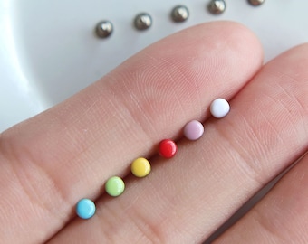 Può includere: Un set di 7 piccole perline rotonde colorate. Le perline sono in ordine arcobaleno, a partire dal blu, poi verde, giallo, arancione, rosso, rosa e bianco.