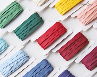 May include: Assortment of colorful ribbon spools on white card stock. The colors include green, red, blue, purple, pink, yellow, and white.