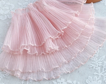 May include: Pink ruffled trim with a delicate, layered design. The trim is made of a soft, sheer fabric and has a scalloped edge.