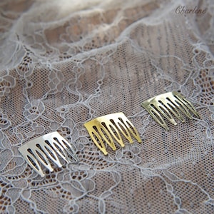 May include: Three gold hair combs on a white lace background. The combs are different sizes and have a decorative design.