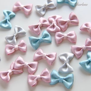 May include: A collection of small, satin-finish ribbon bows in pastel shades of pink, light blue, and silver. Each bow features a central knot detail and smooth, fabric texture. The word Charlene is printed in the upper right corner of the image.