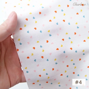 May include: White fabric with a scattered pattern of small, colourful hearts. The hearts are in shades of pink, blue, yellow, and orange. The fabric is labelled with the number "#4".