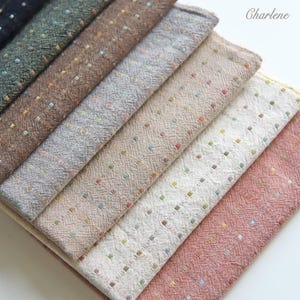 以下が含まれることがあります： 紺色、緑色、茶色、灰色、ベージュ、白、ピンクなど、さまざまな色の生地見本が重ねられています。各見本は、小さなカラフルなドット模様のテクスチャ加工が施されています。「Charlene」という名前が右上に見えます。